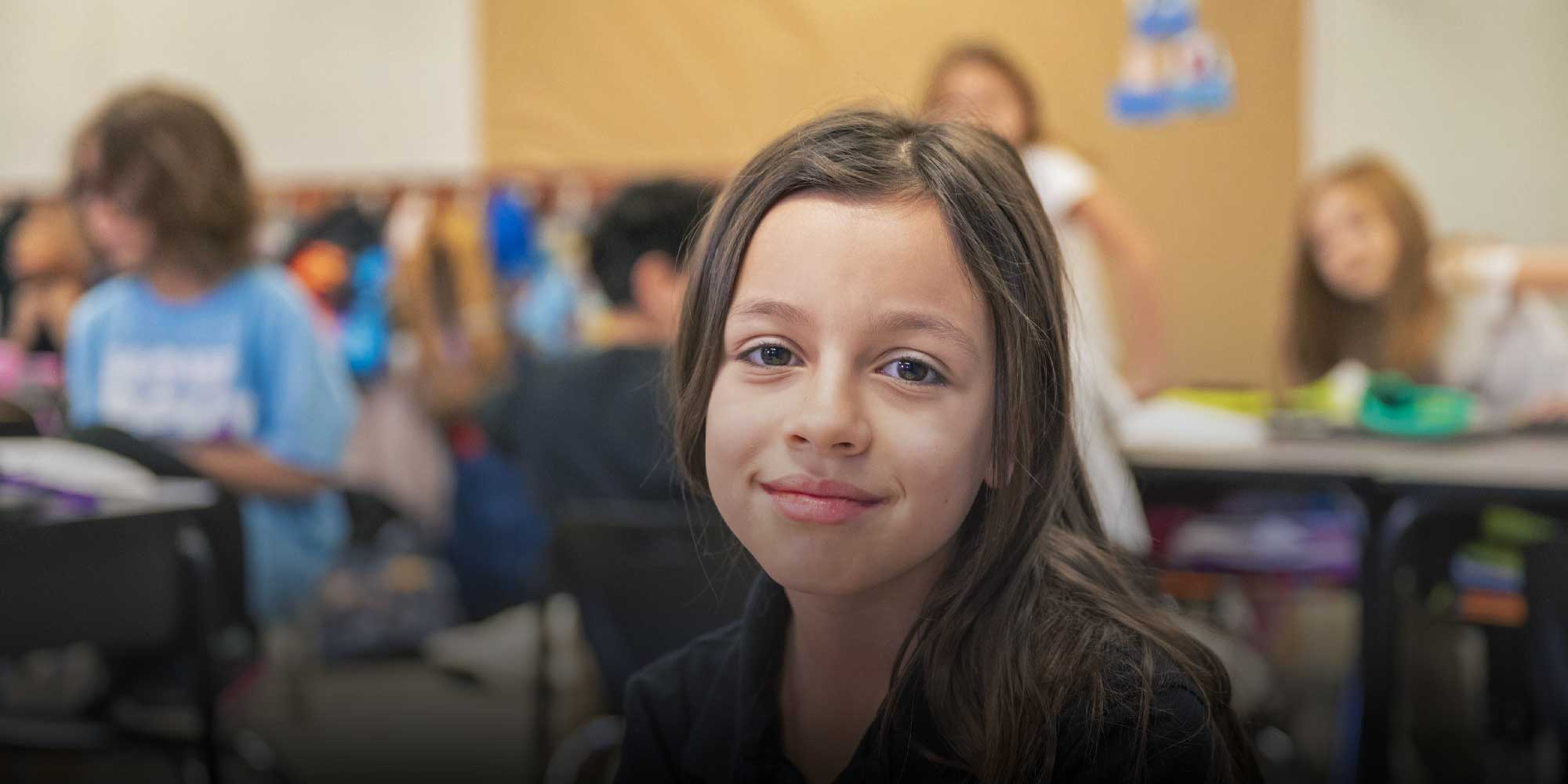 Smiling student sitting in a Parma Academy classroom.