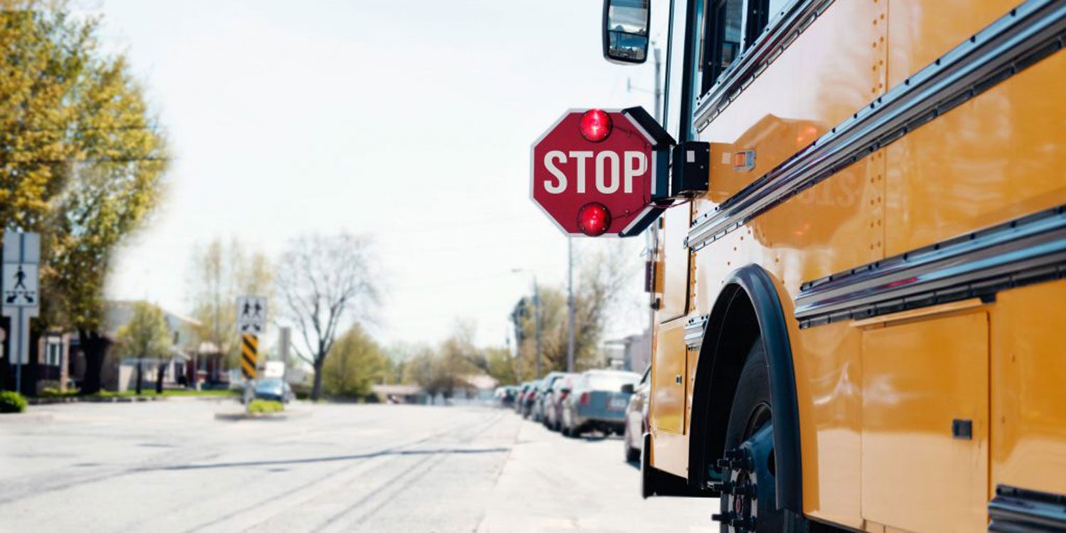 Yellow school bus stopped in a neighborhood with its stop sign extended.
