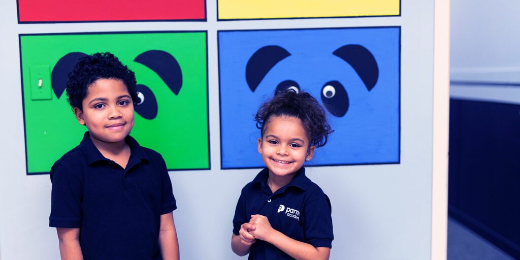 Smiling students standing in front of a wall mural.