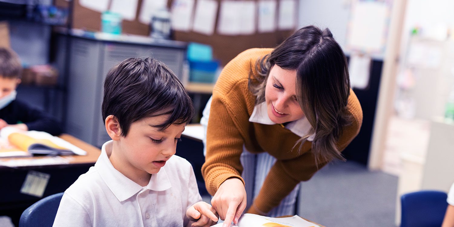 Teacher working with a student in a classroom.